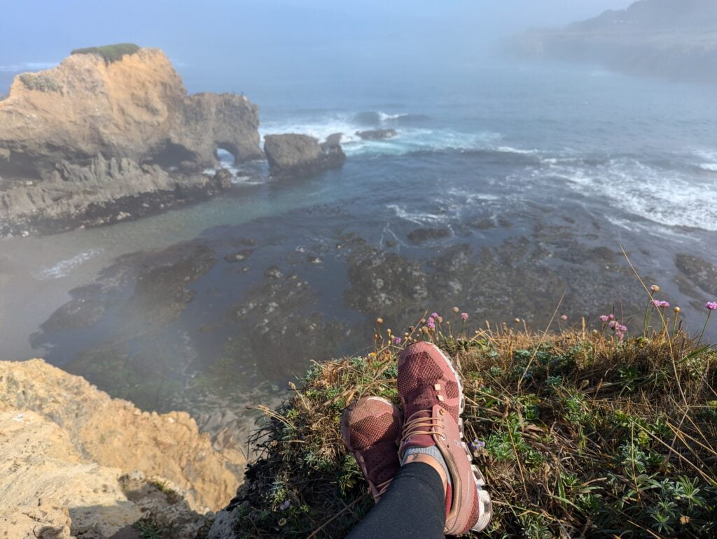 A woman's feet on the edge of a cliff with the ocean view