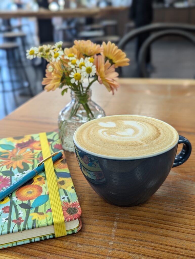 A journal, latte and flowers on a table