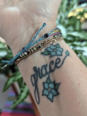 Lisa Fairchild, relationship coach, showing the tattoo on her wrist that says "GRACE"